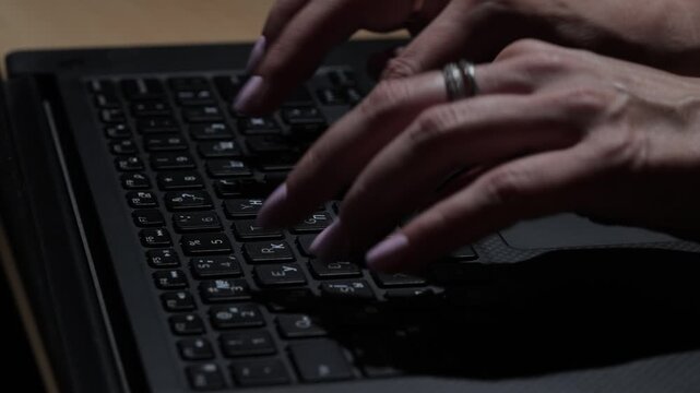 Female professional typing on a laptop in a corporate office environment, shown in close-up with focus on hands, keyboard, business technology, and everyday workplace productivity