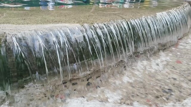 Water cascades gently over stone edge into shallow pool below