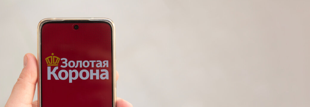 Tbilisi, Georgia - July 24, 2026: Photo banner. Male hand holds mobile phone with logo of payment system KoronaPay, used for cash money transfers. Translation from Russian: Golden Crown. Copy space