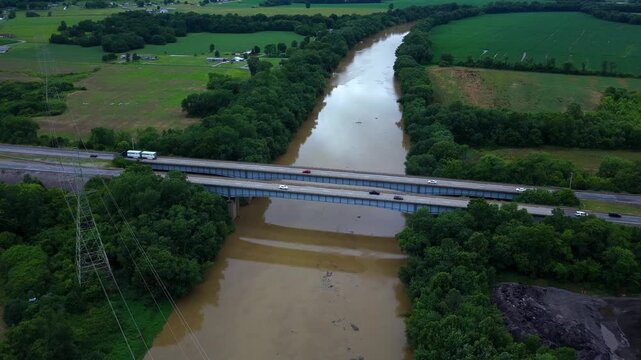 Flood water on Kentucky River with cars traveling across bridge over river as muddy water flows downstream after extreme rain weather event