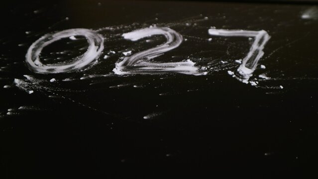 The number zero two seven 027 handwritten in white chalk on a black chalkboard surface.