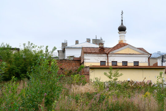 A wasteland overgrown with grass, a brick wall and an old church in Rybinsk, Russia