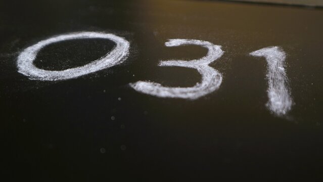 The number zero three one 031 written in white chalk on a black plywood surface