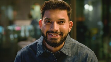 Fototapeta premium Extreme close up portrait Indian business man smiling looking at camera in office company in evening. Headshot ethnic businessman male employer guy specialist startup leader smile positive candid