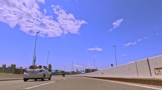 ダイナミックな青空と白い雲が広がる高速道路の風景