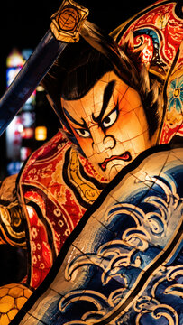 Illuminated warrior lantern float at night festival parade, kabuki face with angry expression, glowing paper sculpture, painted armor patterns, summer street celebration, japanese craft