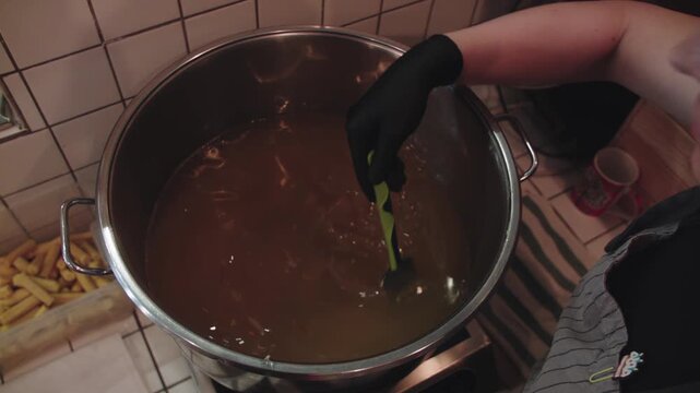 Large stainless steel pot with boiling liquid. Warming up the mixture for making soap at home. Blend of alkali base, base oils, colorants, fillers and additives