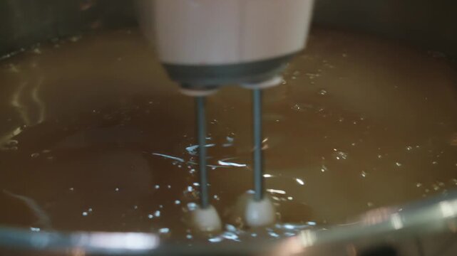Blender thoroughly mixes thick, homogeneous liquid in large saucepan. Housewife cook dissolves gelatin in water. Homemade natural jelly