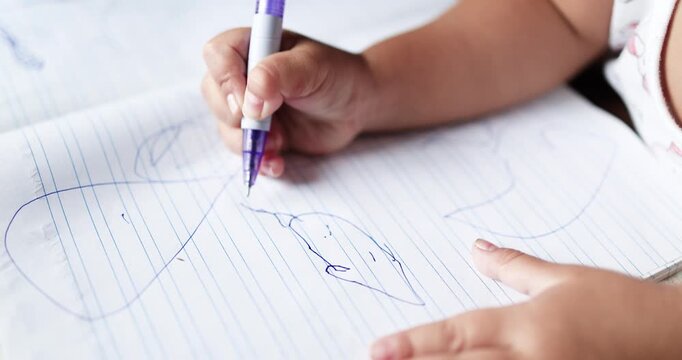 Child drawing in a notebook with a pen, creativity and learning, child development, education, imagination, fine motor skills, and early childhood, close-up