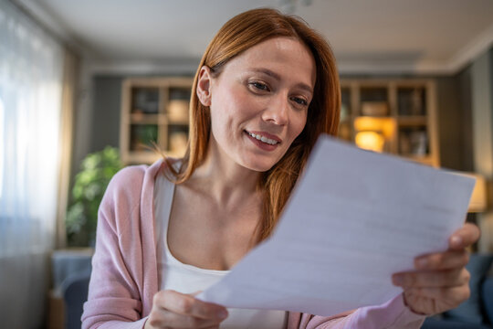 Woman reading letter with happy smiling expression at home