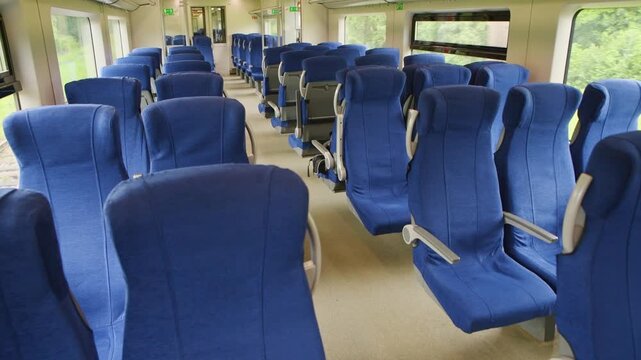Blue upholstered empty passenger seats inside modern train carriage with natural light