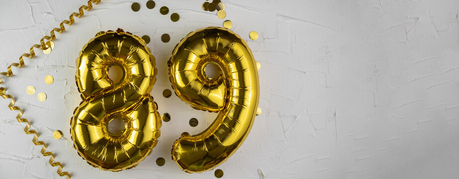 Yellow Gold foil balloon number eighty-nine on white background. Birthday card with lettering 89. Anniversary concept. For anniversary, birthday, wedding event, new year celebration.