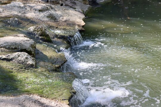 The flowing water in the creek over the rocks.