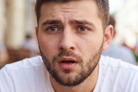 Close-up portrait of a young man with a surprised or shocked expression, open mouth, and furrowed brow.