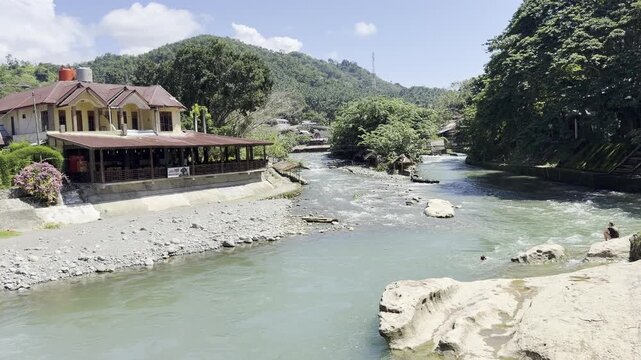 View of the blue Bohorok River flowing through Bukit Lawang. Jungle trekkers often return to the village by traditional tubing and rafting after orangutan tours.