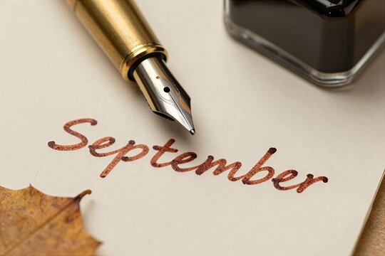 Writing the word September with a fountain pen on a piece of paper near a bottle of ink