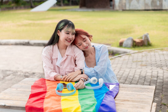 Peaceful lesbian couple resting on each other at a park table
