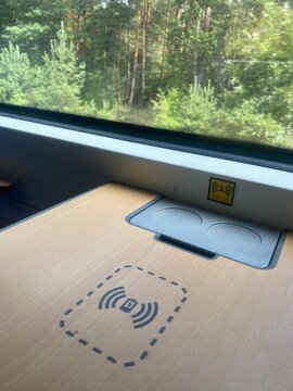 Symbol f&uuml;r kabelloses induktives Laden eines Smartphones im Zug. Moderne Mobilit&auml;t, WLAN, Regionalbahn, ICE, &ouml;ffentlicher Nahverkehr, Reisen und digitale Konnektivit&auml;t.