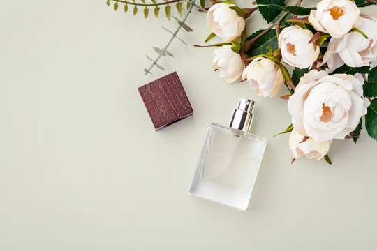 Glass perfume bottle with wooden cap with floral decorations on a pastel green background, copy space