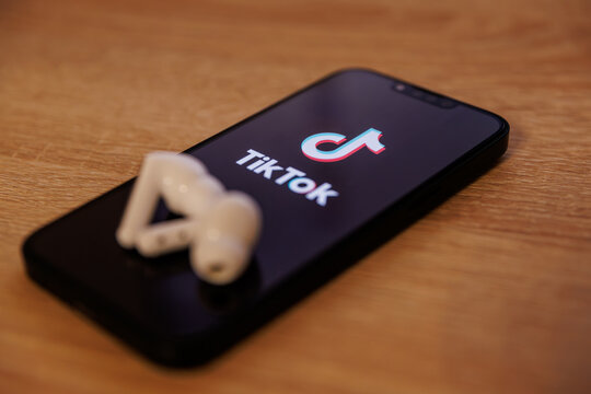 Bălți, Republic of Moldova - July 20 2026: TikTok app logo on smartphone screen and wireless earbuds, mobile social media entertainment and audio listening concept