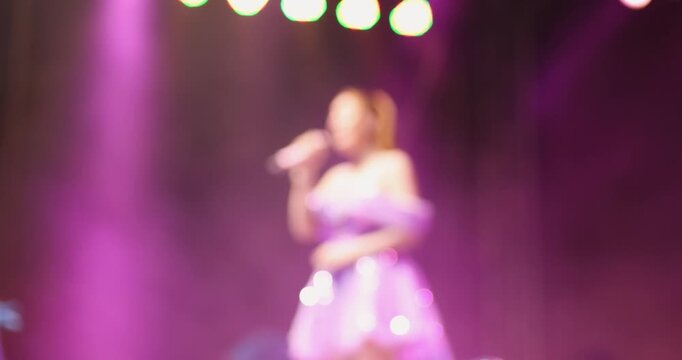 Blurred female singer performing on stage with purple bokeh lights. Perfect for concert, live music, entertainment, event promotion, banners and creative background