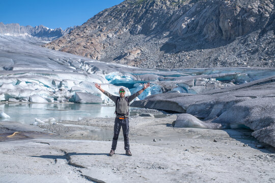 Hiker with Raised Arms on Melting Rhone Glacier in Swiss Alps