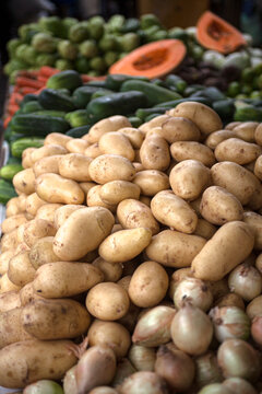 Batatas, cebolas e hortali&ccedil;as frescas expostas em feira livre, destacando produtos agr&iacute;colas da culin&aacute;ria brasileira em mercado popular tradicional.