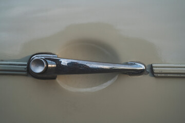 Obraz premium Worn and scratched door handle with push button on a classic retro car, close up detail 