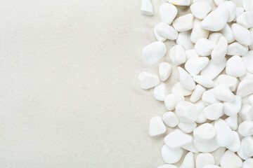 White pebble stones with sand as background, top view © Liami
