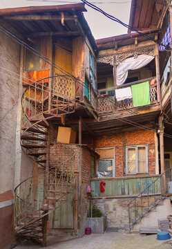 Narrow street lined with traditional residential houses, wooden balconies and aged architecture in the historic district of Tbilisi, Georgia.