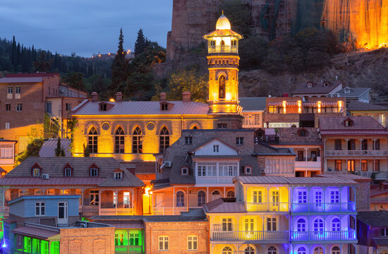 Evening view of the illuminated Jumah Mosque surrounded by traditional houses in the historic district of Tbilisi, Georgia.