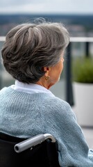 Fototapeta premium Elderly woman in a wheelchair looking at a bright landscape from a terrace on a sunny day