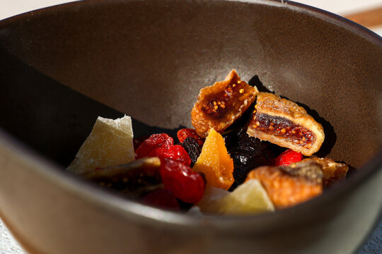 Gourmet dessert featuring dried figs, berries, and candied fruit served in a rustic bowl at a restaurant in Santorini, Greece.