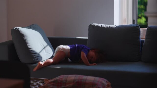 Toddler diving onto sofa at home, highlighting active play, gross motor development and childhood exploration