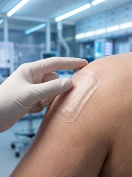 Transdermal patch applied to patient shoulder in clinical laboratory, medical professional wearing white glove placing nicotine or hormone patch, healthcare treatment concept 2026