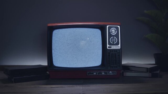 Retro movies television concept, with an old red TV displaying static noise and some videotapes