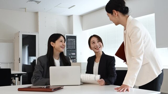 会議で笑顔を見せながら打ち合わせをする20代から40代の日本人ビジネスパーソン3人