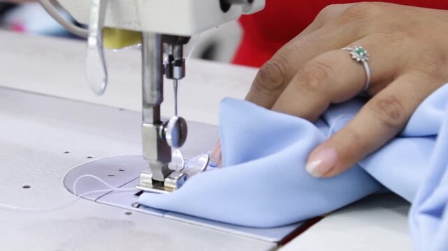 A Latina woman's hands are using a sewing machine to mend an elegant blouse for a client inside a sewing salon in Neiva, Huila, Colombia. Concept of handmade and commercial activity
