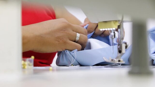 The hands of a Hispanic seamstress are mending an elegant blouse with a small pin for a client on a table inside a sewing salon in Neiva, Huila, Colombia. Concept of handmade
