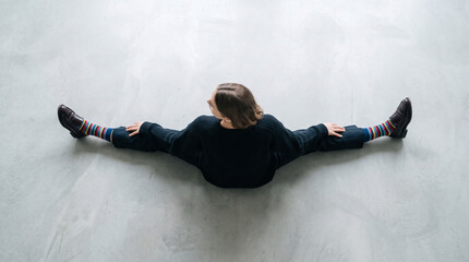 Obraz premium Woman doing a split on a light gray floor, showcasing flexibility, comfort, and unique colorful socks