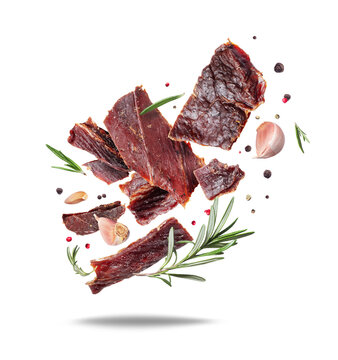 Delicious beef jerky with rosemary and garlic in the air isolated on a white background