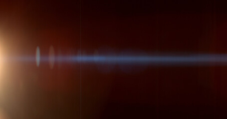 Obraz premium Warm anamorphic lens flare overlay featuring a golden light source, blue horizontal light streak, realistic optical reflections and subtle glow on a black background. Premium VFX asset.