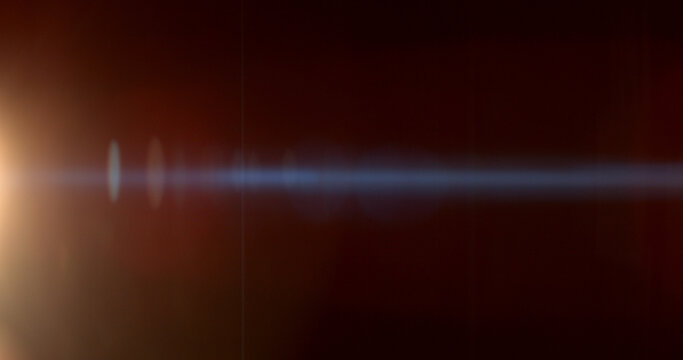 Warm anamorphic lens flare overlay featuring a golden light source, blue horizontal light streak, realistic optical reflections and subtle glow on a black background. Premium VFX asset.