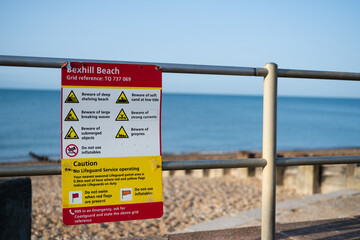 Beach hazard information sign at Bexhill Beach beside a seaside promenade © Jane Allan