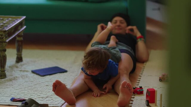 Toddler sliding down mother&rsquo;s legs during play at home, highlighting active play, coordination and family connection