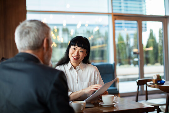 Smiling businesswoman meeting client over coffee in modern cafe