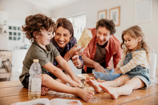 Happy family baking dough together in home kitchen