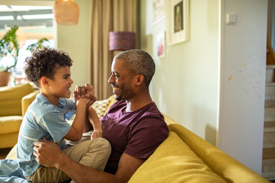 Father and son playing on sofa at home