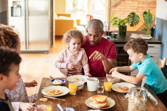 Father and children eating pancakes at home kitchen table