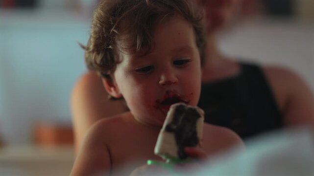 Toddler with chocolate covered face after eating ice cream, highlighting messy eating, self feeding and authentic childhood